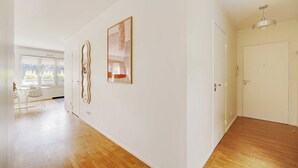 Une pièce spacieuse dotée d’un plancher en bois, d’un coin repas avec une table et des chaises, et de deux œuvres d’art encadrées accrochées au mur.