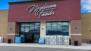 A Madison Foods store with a maroon facade, large windows, and a parking lot in front. - Mountain View Retreat (Ennis)