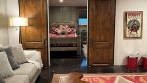 A room with a bed, a couch, a lamp, and a poster on the wall. - Mountain View Retreat (Ennis)