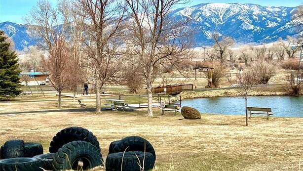 A park with picnic tables, benches, and a lake. - Mountain View Retreat (Ennis)