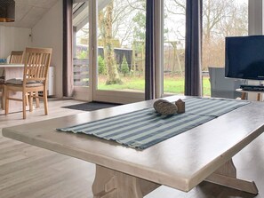 A room with a large window, a dining table with chairs, and a television. - 4 Person Holiday Home in Hemmet (Hemmet)