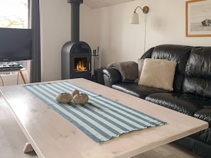 A living room with a black leather sofa, a wooden coffee table with a striped rug, a fireplace, and a television. - 4 Person Holiday Home in Hemmet (Hemmet)