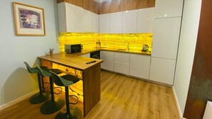 A compact kitchen with a wooden countertop, bar stools, and white cabinets. - city center 1-bedroom apartment with WiFi and AC in delightful Shkodër (Shkodër)
