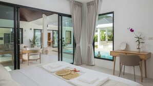 A modern bedroom with a large bed, a desk, and a view of a swimming pool.