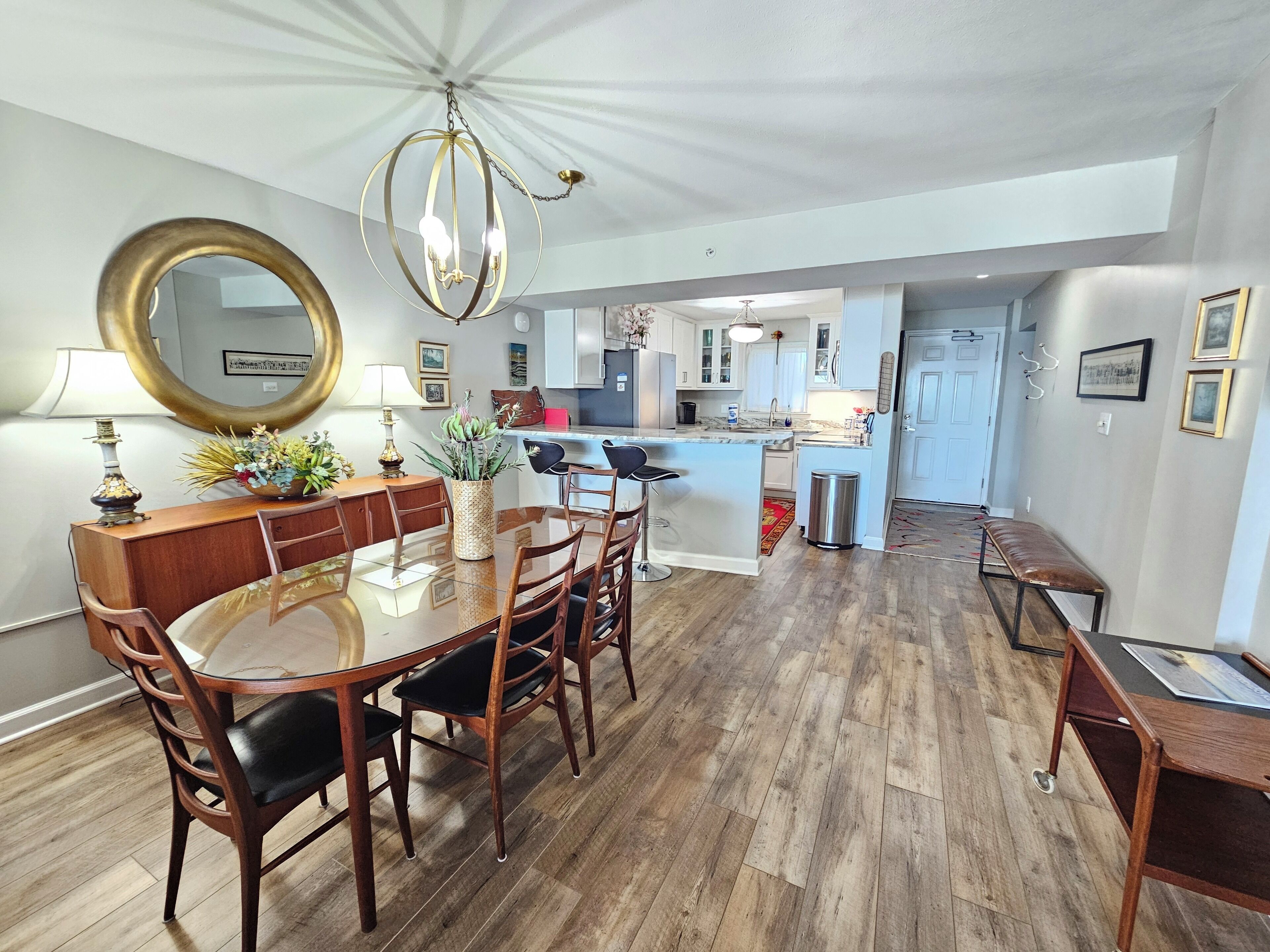 A modern kitchen with white cabinets, a central island, and a dining area with a round table and chairs.