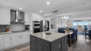 A modern kitchen with white cabinets, stainless steel appliances, and a central island. - Sandy Key 816: 2 BR/2 BA Perdido Key Beachfront Condo, On-Site Rental Office, Sleeps 6 (Pensacola)