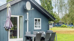 Un edificio azul con mesa y sillas en el patio, una puerta corredera de vidrio y una antena parabólica.