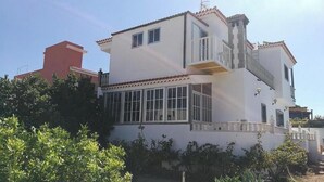 Un immeuble de deux étages doté d’un balcon, de grandes fenêtres et d’une cheminée rouge.