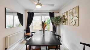 Un espace repas comprenant une table, des chaises, un ventilateur de plafond, un radiateur et des éléments de décoration murale.