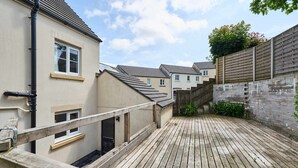 Une terrasse en bois offrant une vue sur des immeubles résidentiels, un mur de briques et une clôture en bois.