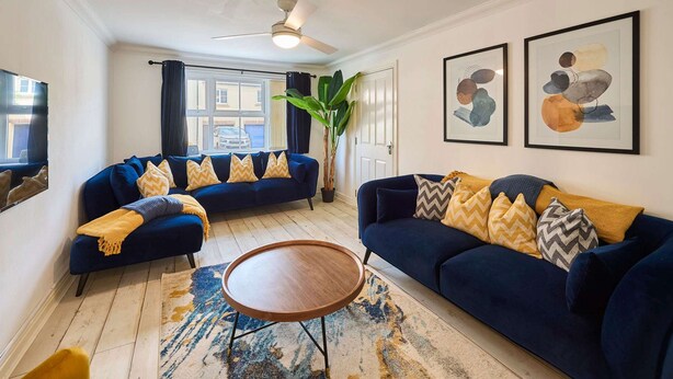Un salon avec un canapé bleu, une table basse ronde et une grande plante.