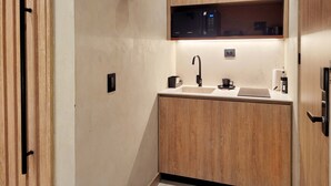 A compact kitchen with wooden cabinetry, a modern faucet, and a built-in microwave. - w Sophisticated 1BR w Terrace in El Poblado (Medellín)