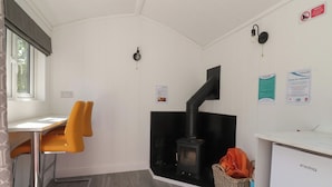 Eine kompakte Küche mit Holzofen, Essbereich mit zwei Stühlen, kleinem Kühlschrank und einem Korbwäscheschrank.