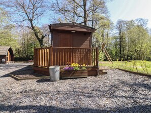 A wooden cabin with a porch, surrounded by gravel and trees. - Butterfly Hut 2 (Preston)