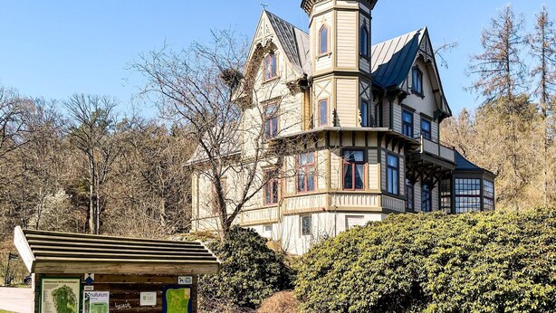 A historic building with a tower, multiple windows, and a signboard in the foreground. - 4 Star Holiday Home in Ronneby (Ronneby)