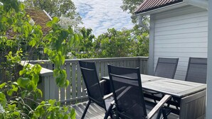 A wooden deck with a table and chairs, surrounded by greenery and trees. - 4 Star Holiday Home in Ronneby (Ronneby)