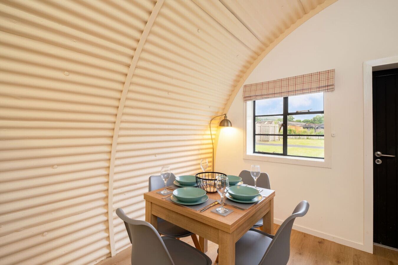 A dining area with a table set for four, a window with a view, and a lamp.
