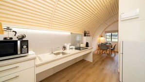 A modern kitchen with a microwave, sink, and dining area with chairs and a table.