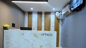 A reception desk with a marble top and the word "RECEPTION" on it. - Hotel Lavit (Ahmedabad)