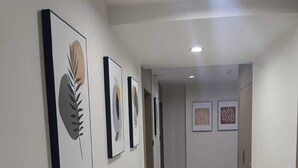 A hallway with framed artwork on the walls, a marble floor, and a door at the end. - Hotel Lavit (Ahmedabad)