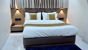 A modern hotel room with a large bed, two bedside tables, and a headboard with integrated lighting. - Hotel Lavit (Ahmedabad)