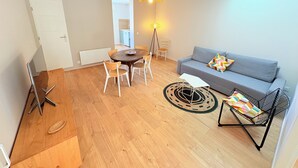 A modern living room with a grey sofa, wooden dining table, and chairs. - Biarritz near Côte des Basques - T2 renovated (Biarritz)