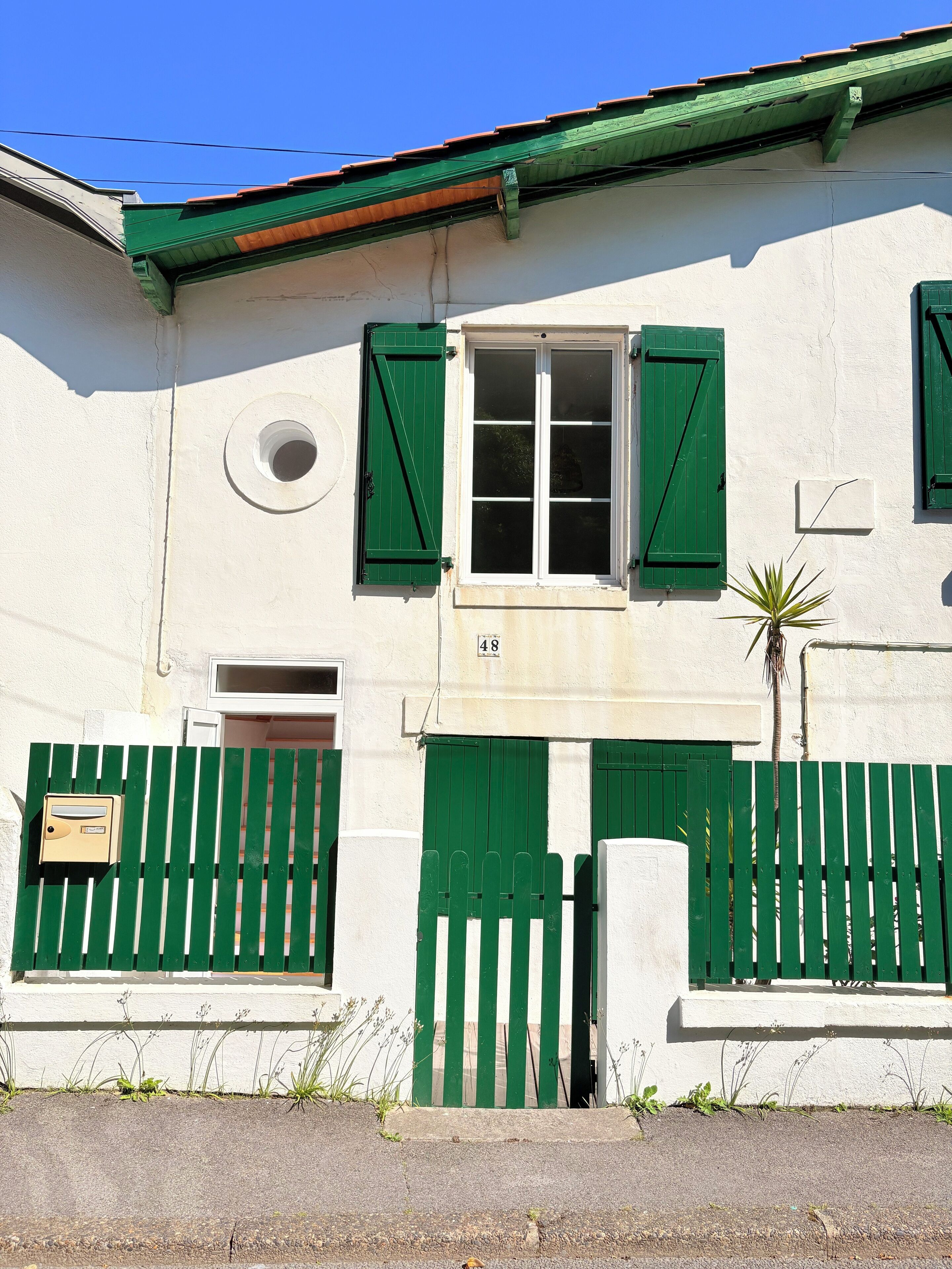 A building with a white facade, green shutters, and a numbered door.
