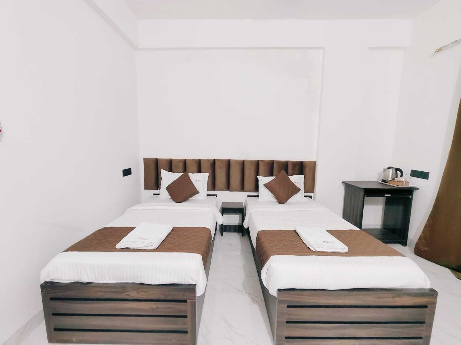 Een hotelkamer met twee bedden, een tafeltje en een nachtkastje.