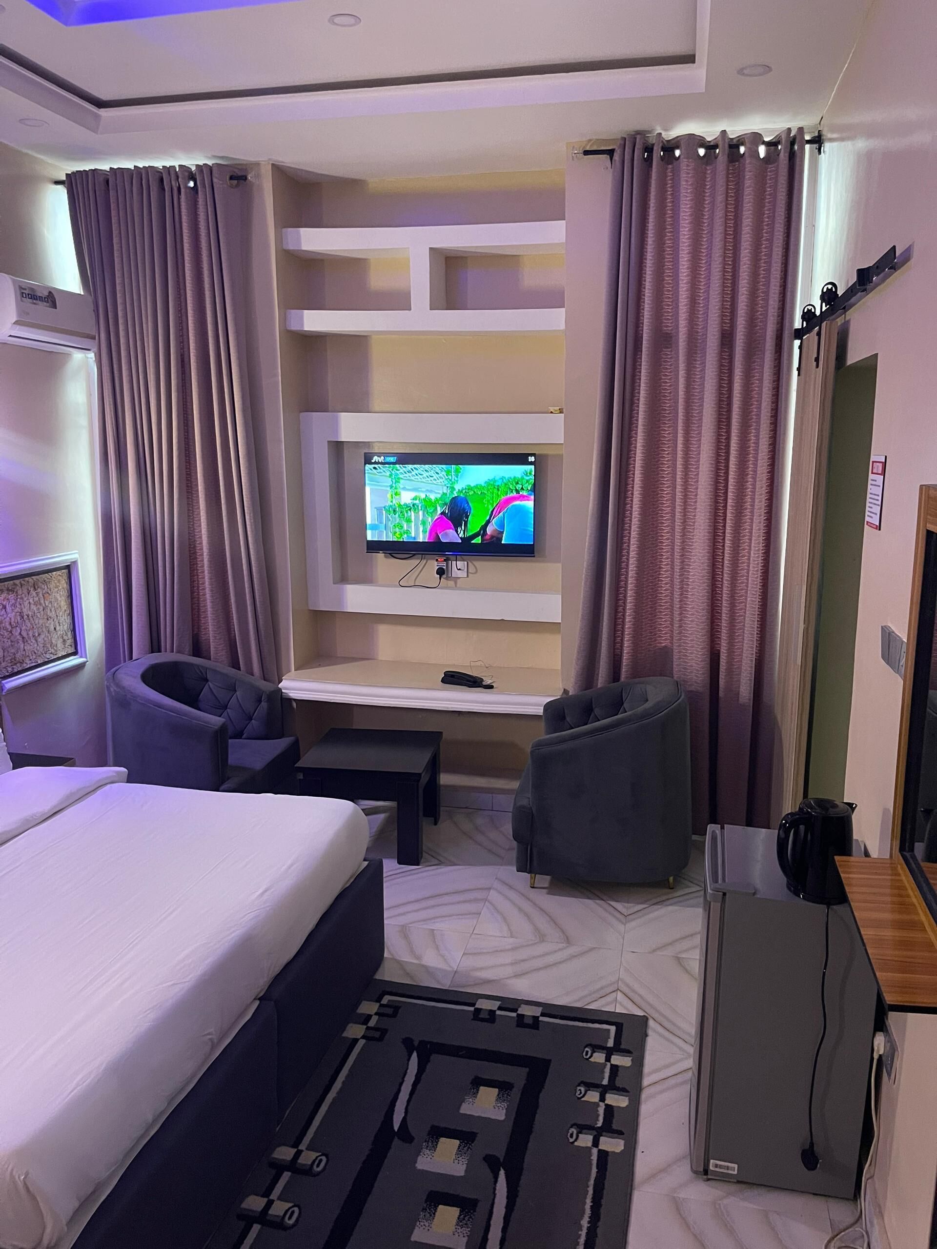 A hotel room with a bed, a desk, a television, and two chairs.