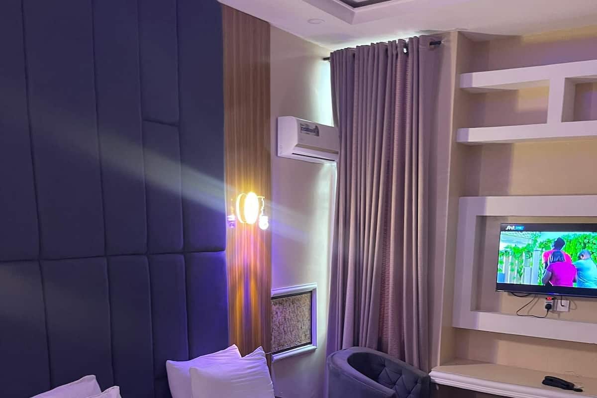 Ett hotellrum med en stor säng, ett skrivbord, en stol och en tv.