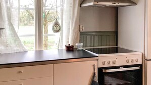 Une cuisine équipée d’une cuisinière, d’un four et d’une fenêtre avec des rideaux.