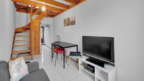 Un salon moderne avec un escalier en bois, un téléviseur à écran plat et un coin repas.