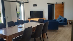 A modern living room with a dining area, a TV, and a large window.