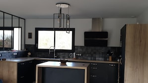 A modern kitchen with a large window, a central island, and a built-in oven.