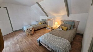 A cozy loft bedroom with a loft bed, a smaller bed, and a bedside table with a lamp.