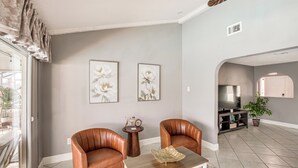 Una sala de estar con dos sillones de cuero, una mesa de centro y dos cuadros con motivos florales en la pared.