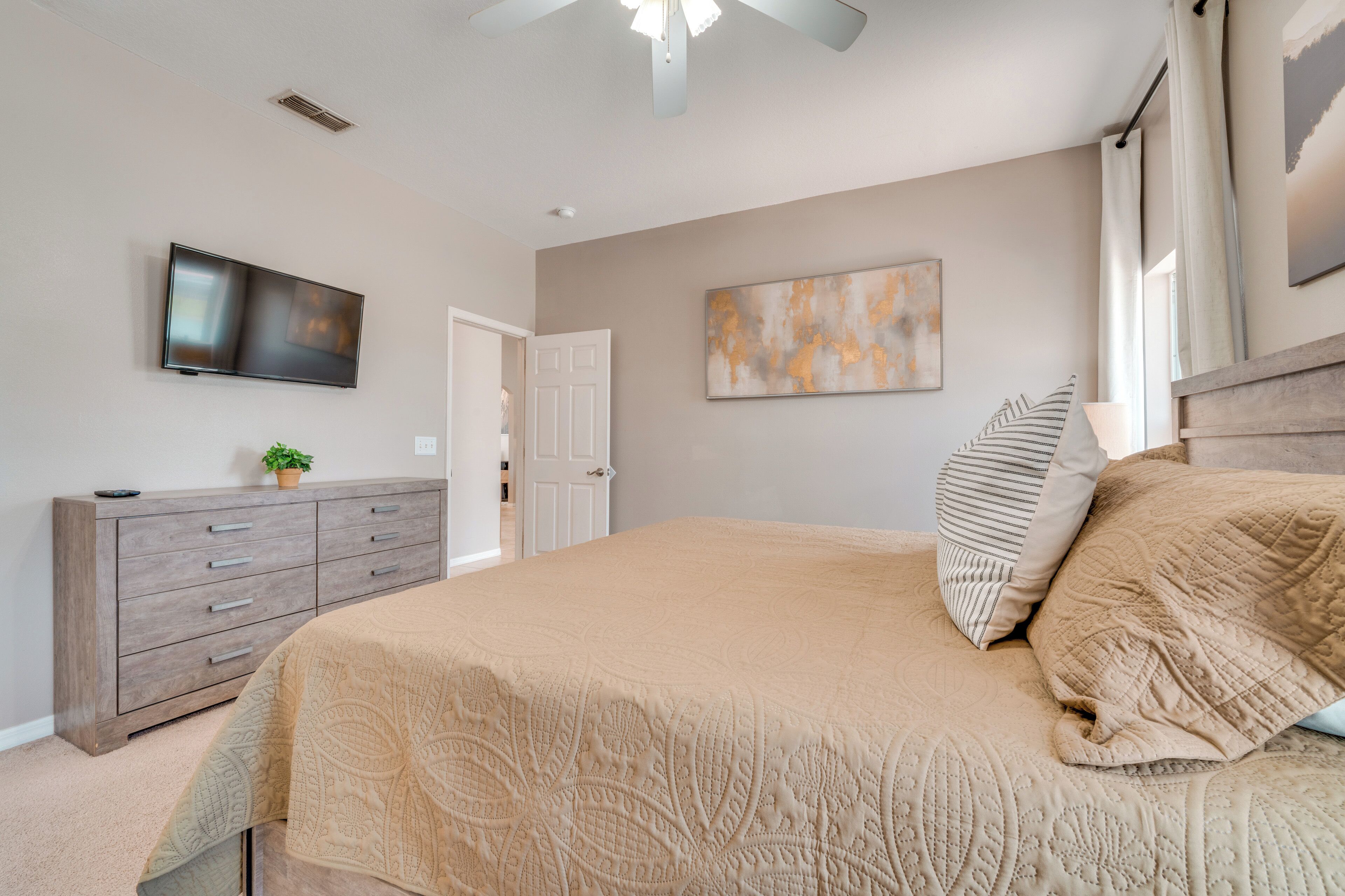 A bedroom with a bed, a dresser, a TV, and a door.