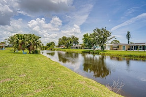 A residential area with a calm pond, green lawns, and houses with large windows. - Pool & Spa: Canal-front Home Near Beaches (Rotonda West)