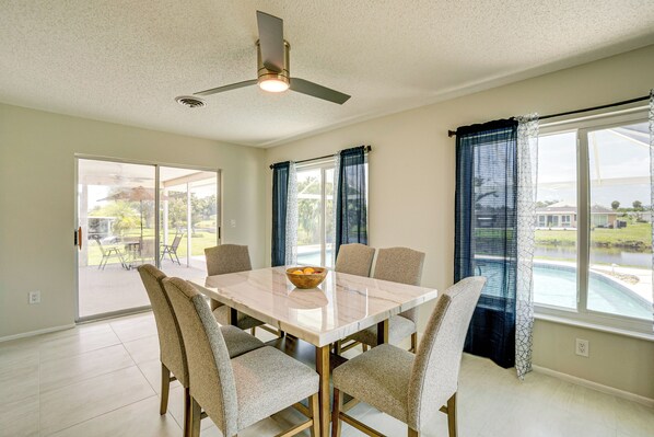 A dining area with a marble table, six chairs, and a ceiling fan. - Pool & Spa: Canal-front Home Near Beaches (Rotonda West)
