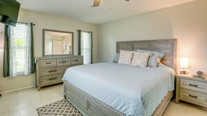 Een slaapkamer met een bed, nachtkastjes, een dressoir, een plafondventilator en een spiegel.