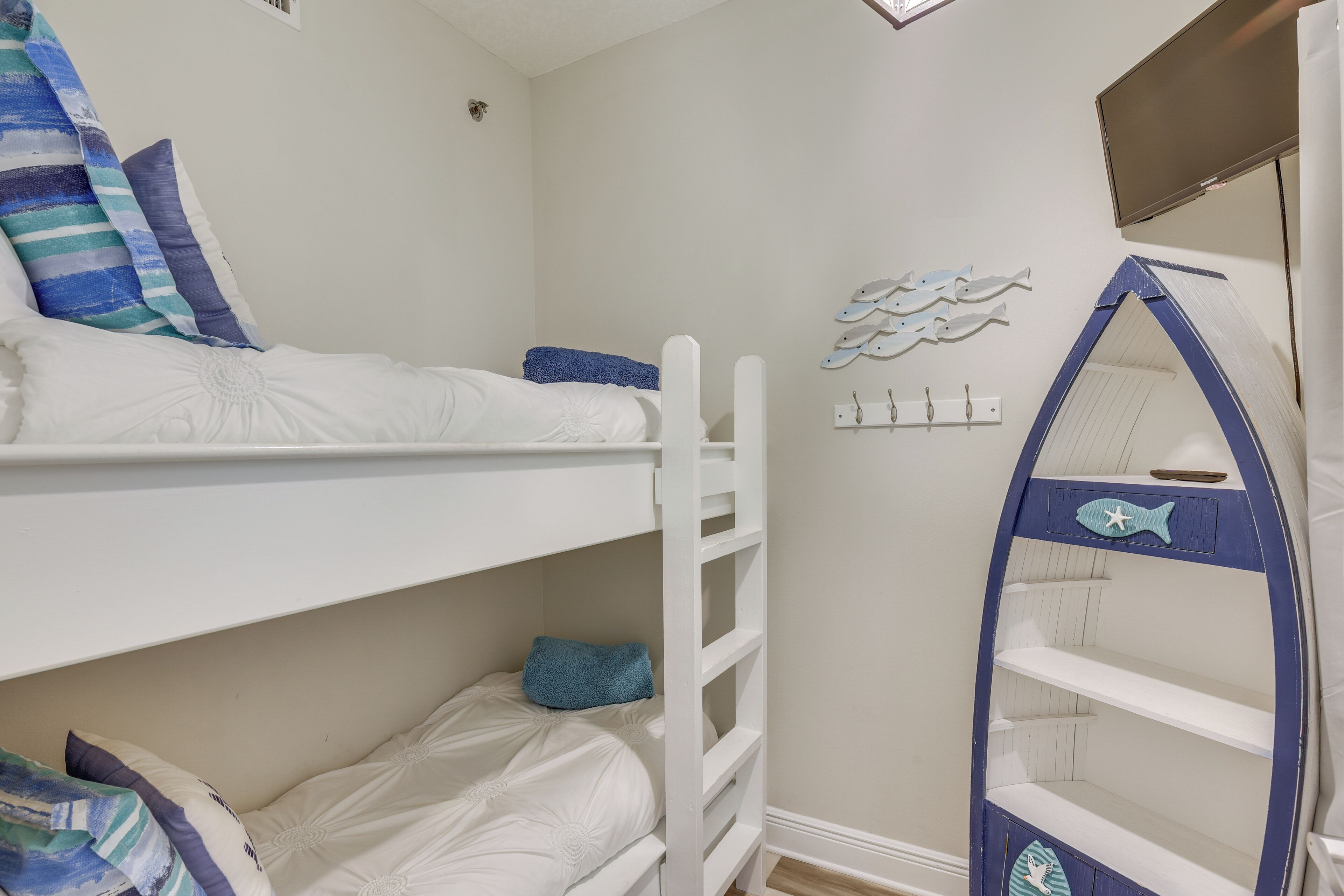 Une chambre avec des lits superposés décorée sur le thème de la marine, comprenant une étagère en forme de poisson et des décorations murales.