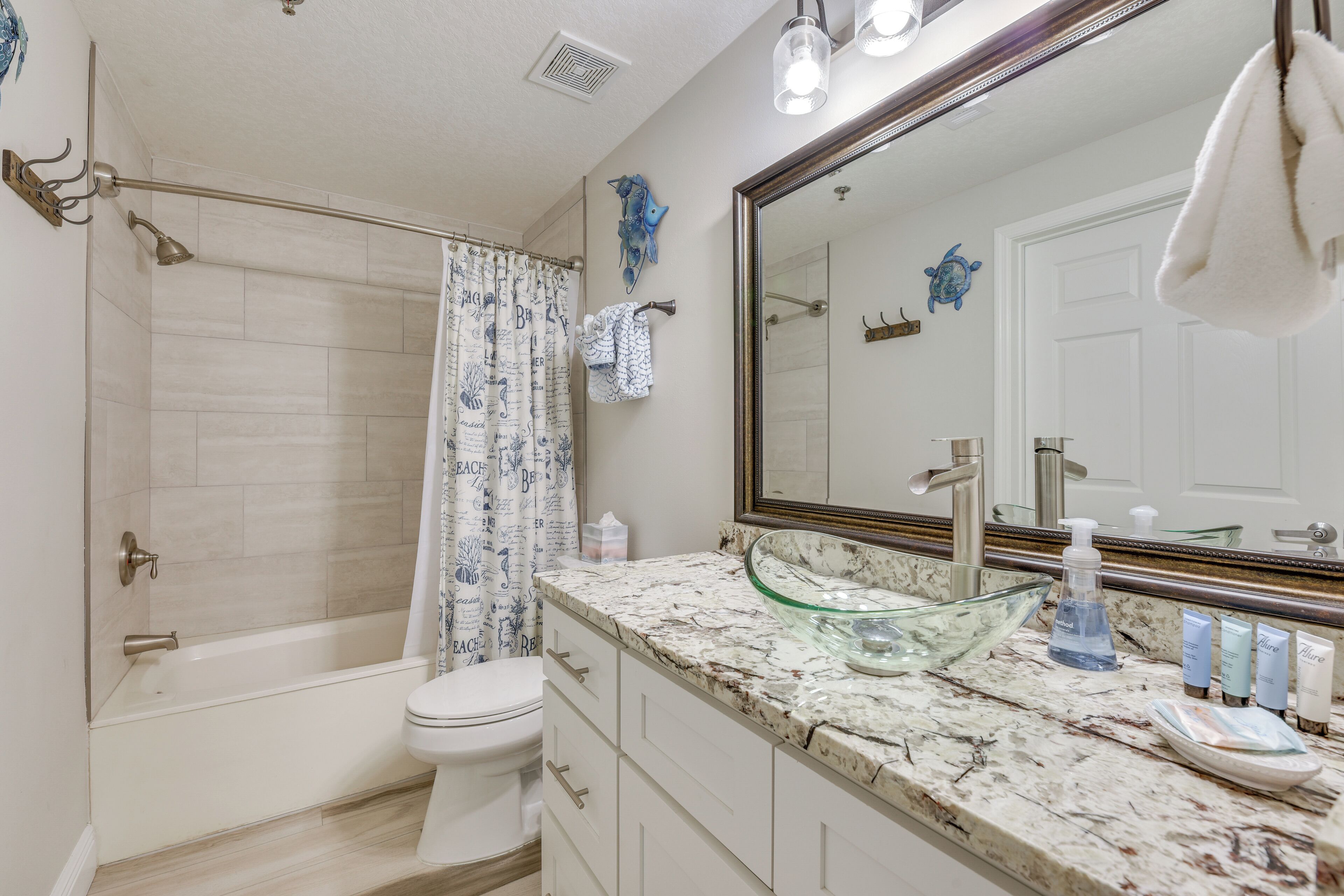 A bathroom with a bathtub, toilet, and a large mirror.