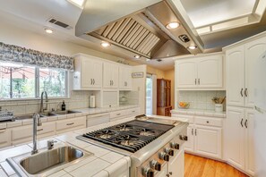 A modern kitchen with white cabinetry, a stainless steel range, and a large window providing natural light. - 10 Mi to Redding: Serene Escape w/ Spacious Yard! (Anderson)