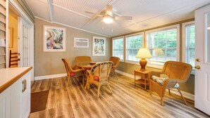 A room with a ceiling fan, wicker furniture, a dining table, and large windows. - Fish, Relax & Repeat: Home w/ Yard in Eastpoint! (Eastpoint)