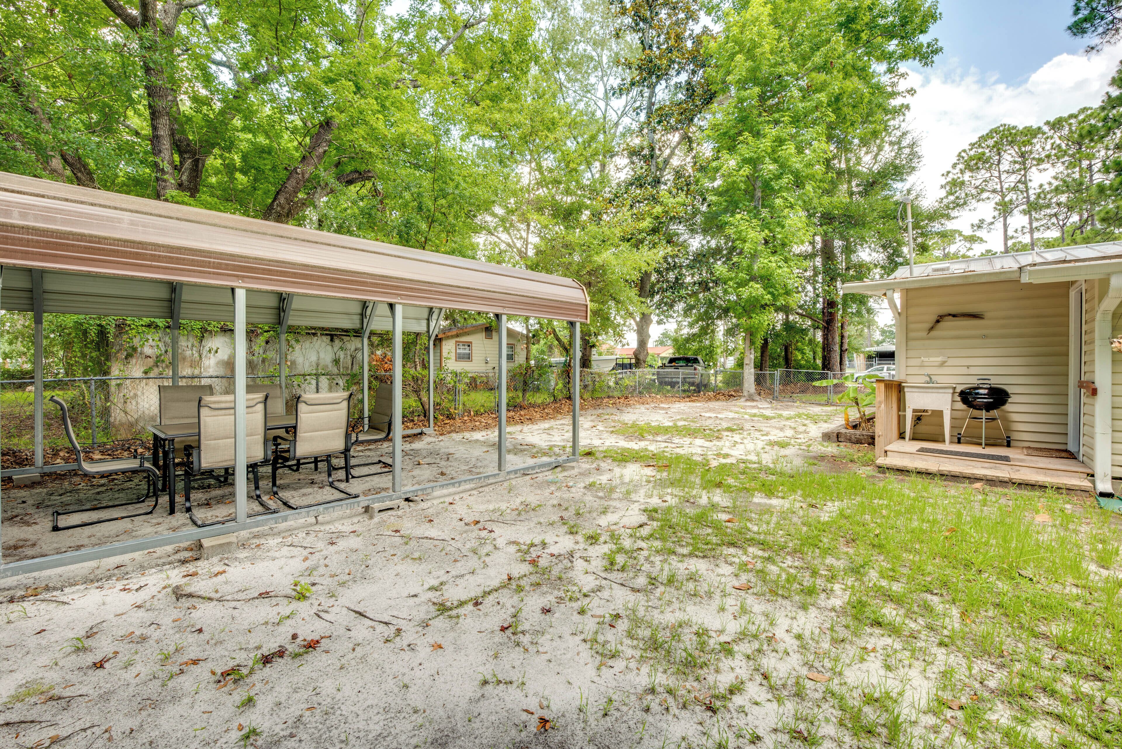 Un'area patio coperta con tavoli e sedie, un barbecue e un piccolo edificio con veranda.
