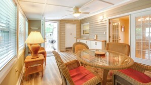 A dining area with wicker furniture, a glass table, and a ceiling fan. - Fish, Relax & Repeat: Home w/ Yard in Eastpoint! (Eastpoint)