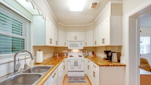 A compact kitchen with white cabinets, a stainless steel sink, a microwave, and a stove. - Fish, Relax & Repeat: Home w/ Yard in Eastpoint! (Eastpoint)