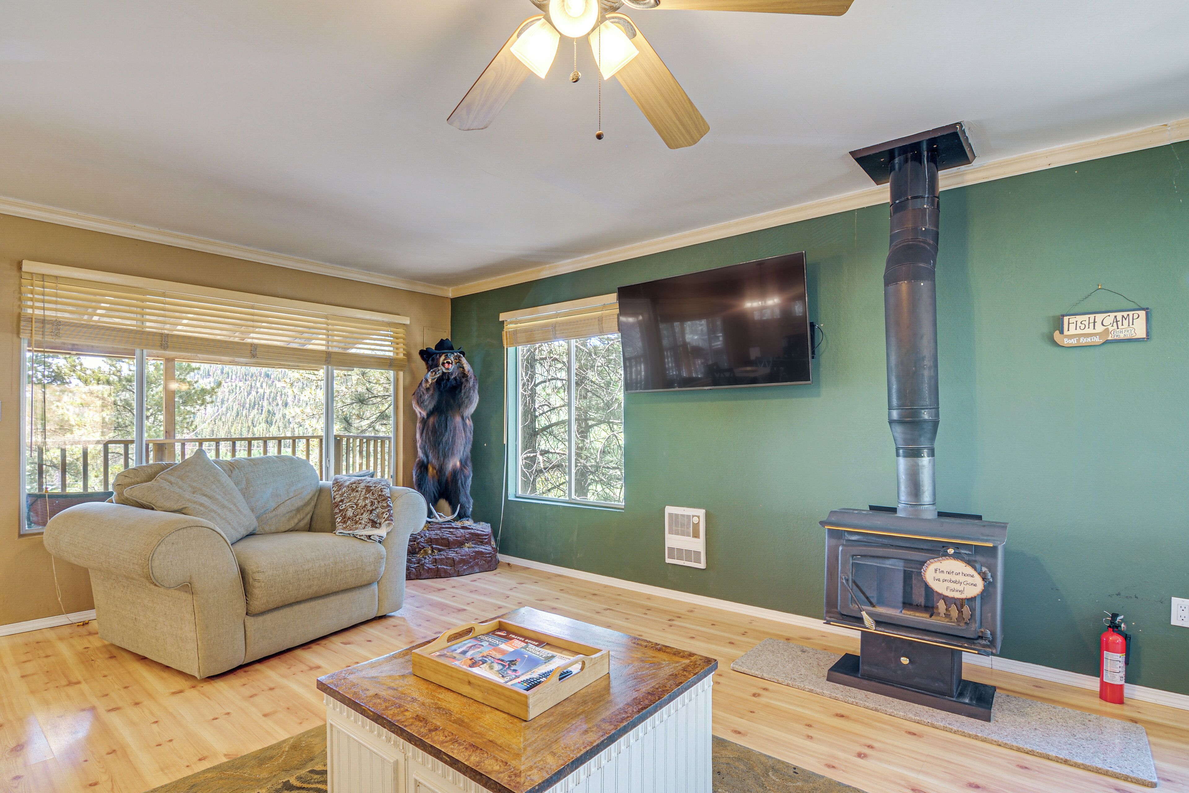 A cozy living room with a sofa, a coffee table with a book, a fireplace, and a ceiling fan.