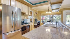 A kitchen with stainless steel appliances, wooden cabinets, granite countertops, and a large window providing natural light. - Furnished Deck & Mountain Views: Panguitch Cabin (Panguitch)