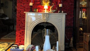 A room with a fireplace, a clock, and a table with flowers and candles. - The Abigail Manor-A night with Marilyn Monroe (Manistee)